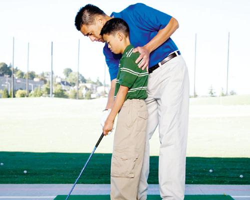 Father teaching his son how to golf.